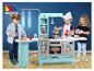 Des enfants jouent avec une cuisine en plastique bleue avec un four, un réfrigérateur et une machine à laver.