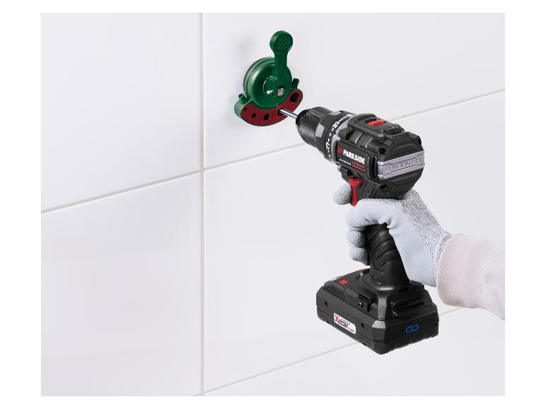 Une perceuse perce des carreaux à l'aide d'un outil de guidage vert.