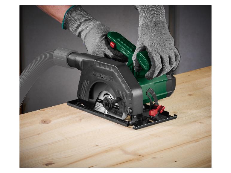 Une personne gantée utilise une mini scie circulaire Parkside sur une surface en bois.