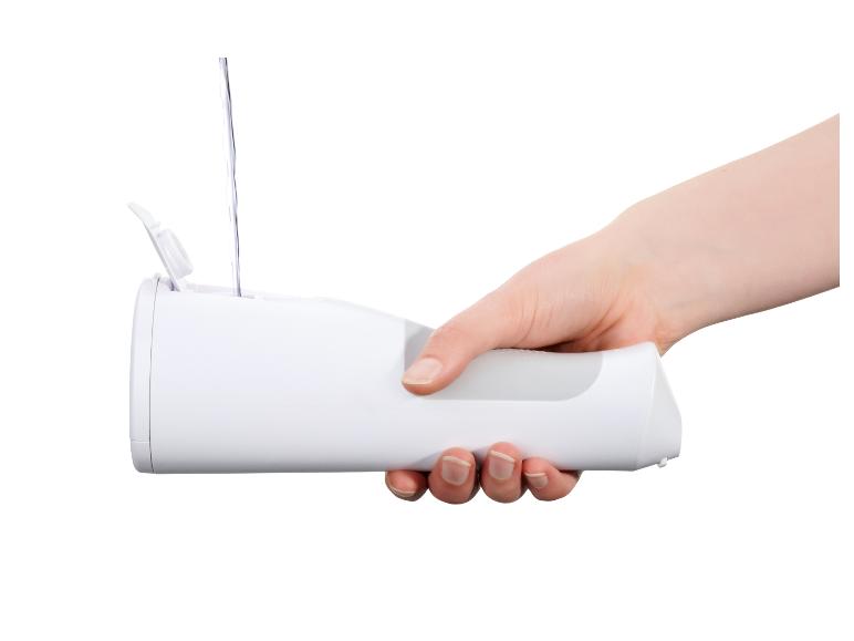 Main tenant un hydropulseur blanc rempli d'eau.