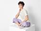 Une femme porte un t-shirt blanc, un pantalon violet et des baskets blanches.