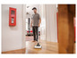 Un homme nettoie un sol en bois avec un aspirateur Karcher.