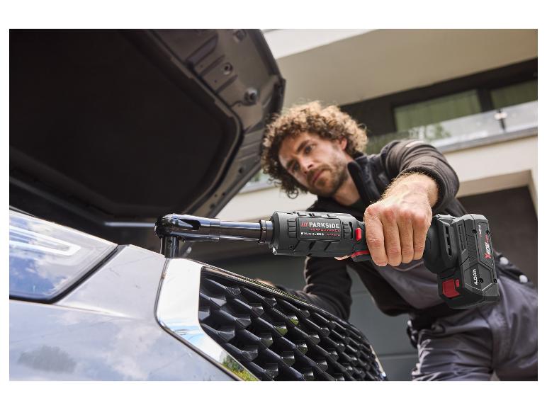 Un homme utilise le cliquet sans fil 20 V PARKSIDE PERFORMANCE sur le moteur d'une voiture.