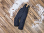 Pantalon de ski noir avec bretelles sur un sol en bois avec de la neige
