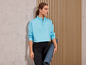 Une femme en sweat-shirt bleu et leggings noirs tient un tapis de yoga.
