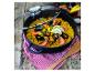 Paella aux fruits de mer dans une cocotte noire avec couvercle en verre et logo ELO sur table en bois.