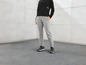 Une femme porte un pantalon de survêtement gris et des baskets noires.