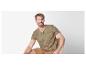 Homme assis sur une chaise avec une chemise beige à motif tropical.