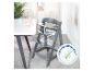 Chaise haute grise pour bébé à côté d'une table avec vaisselle et jouets pour enfants, avec certificat de sécurité.