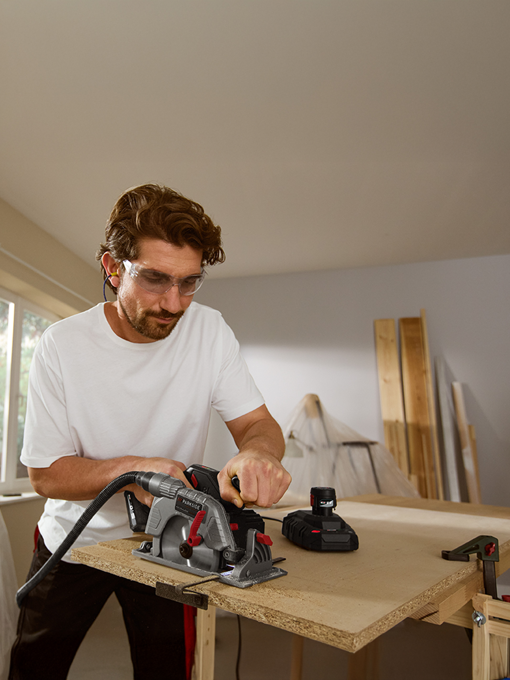 Homme coupant une planche de bois avec une scie circulaire Parkside.