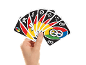 Main tenant un éventail de cartes de jeu colorées sur fond noir.