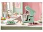 Robot culinaire vert pastel sur un comptoir avec des gâteaux et des pâtisseries.