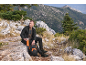 Homme en veste polaire et pantalon de trekking assis sur un rocher avec sac à dos et bouteille.