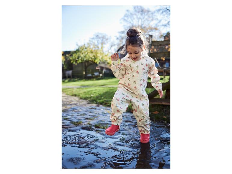 Un enfant dans un imperméable à motif papillon saute dans une flaque.