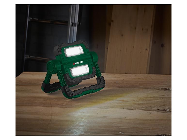 Lampe de travail verte PARKSIDE sur surface en bois, avec faisceaux lumineux