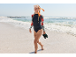 Femme en haut à manches longues, bas de bikini et masque de plongée marchant sur la plage.