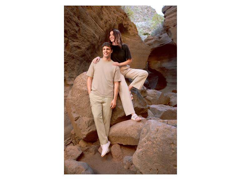 Homme et femme en tenues décontractées beiges et noires, debout parmi les rochers.