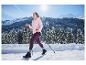Femme en veste softshell thermique CRIVIT et leggings violets marchant dans un paysage montagneux enneigé.
