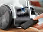 Un aspirateur gris avec un embout noir.