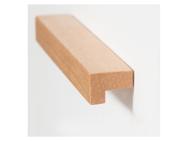 Une pièce de bois clair avec une encoche, montée sur un mur blanc.