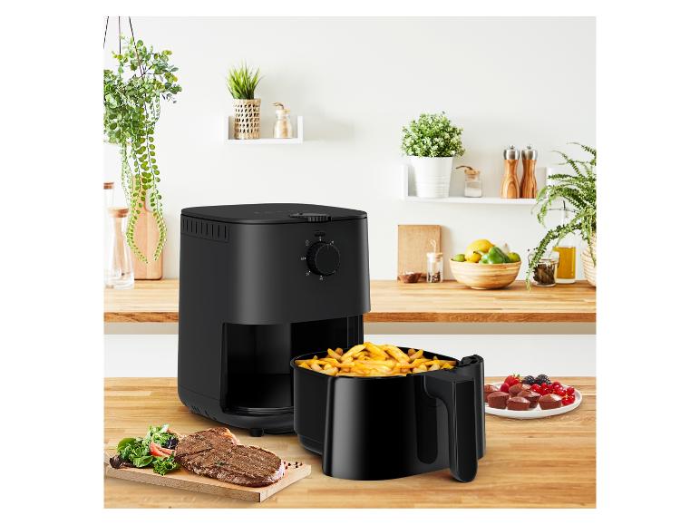 Friteuse à air noire avec frites, steak et dessert dans une cuisine.
