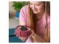 Une femme tient un moule rond rose avec un dessert aux biscuits Oreo et aux baies de goji.
