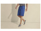 Un homme portant un short bleu et des espadrilles grises.