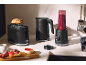 Grille-pain, bouilloire et blender noirs sur un plan de travail de cuisine.