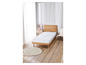 Un matelas blanc sur un cadre de lit en bois dans une chambre claire.