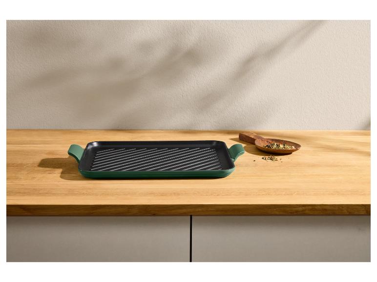 Poêle à griller verte sur un comptoir en bois avec une cuillère en bois d'épices.