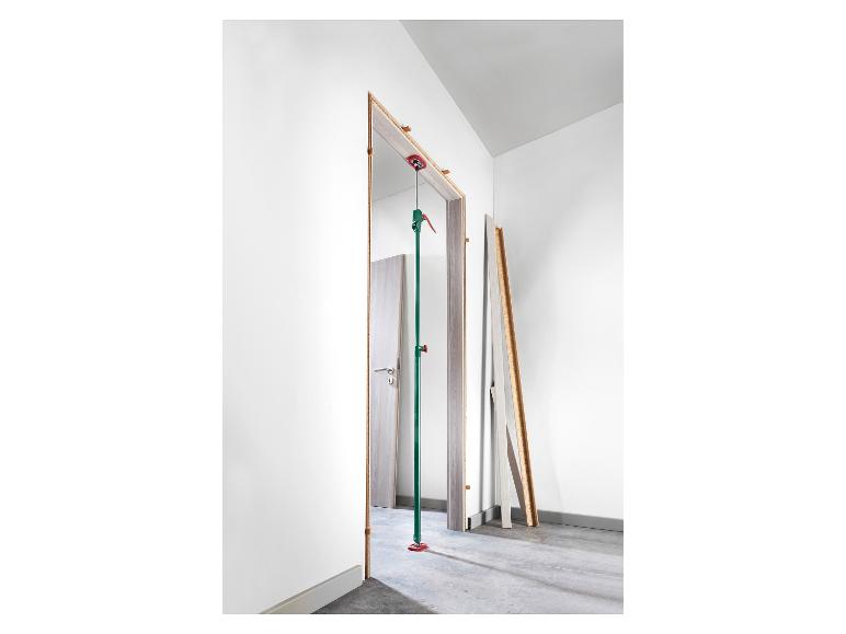 Installation d'un cadre de porte avec une béquille télescopique verte et rouge dans une pièce blanche.