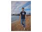 Homme en t-shirt bleu marine et jean sur une plage de sable.