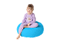 Fille souriante en pyjama violet assise sur un pouf bleu