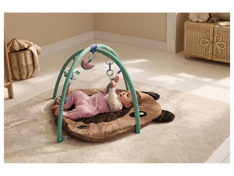 Bébé allongé sur un tapis d'éveil LUPILU® avec arche et jouets suspendus.