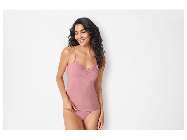 Une femme porte un débardeur rose à dentelle et des sous-vêtements assortis.