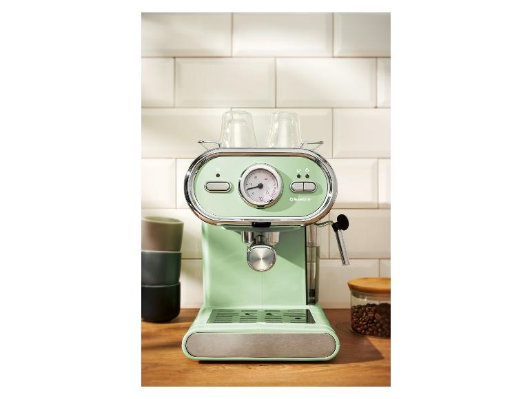 Machine à expresso vert menthe avec tasses en verre sur un comptoir en bois.