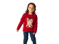 Fillette souriante portant un pull rouge avec un ourson et un jean.