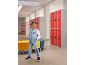 Garçon en veste de jogging bleu clair et pantalon assorti dans un couloir d'école avec des casiers rouges.