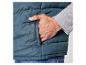 Un homme porte un gilet matelassé bleu foncé avec sa main dans la poche.
