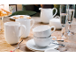 Mugs, tasses, soucoupes, crémier et sucrier en porcelaine blanche sur une table en bois avec flûtes à champagne et biscuits en forme d'étoile.