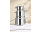Pile de quatre casseroles et poêles en acier inoxydable sur une surface en marbre blanc.