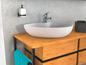 Un lavabo de salle de bain avec un robinet, un distributeur et une armoire en bois avec des tiroirs.
