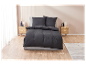Parure de lit noire sur un lit gris dans une chambre moderne.