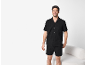 Homme souriant en pyjama d'été noir, chemise à manches courtes et short.