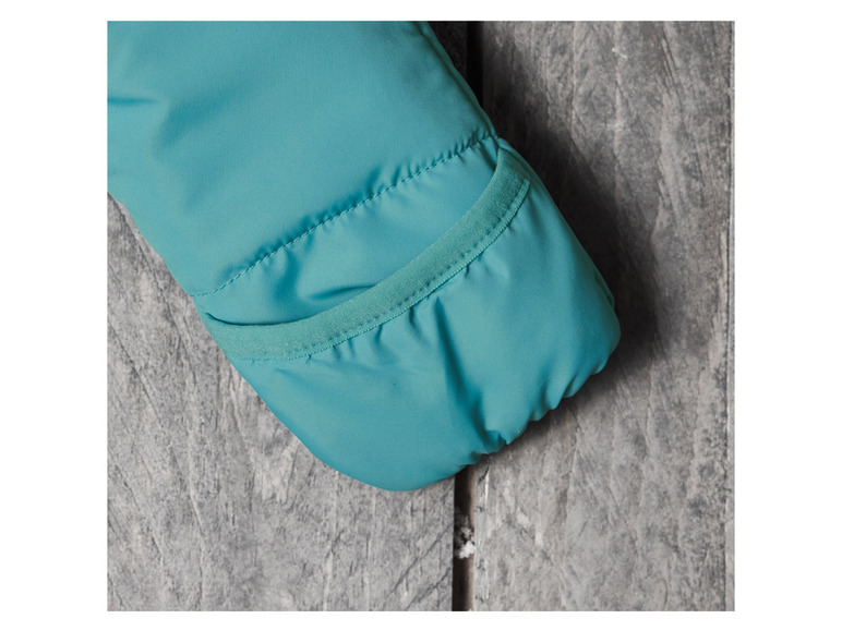 Gros plan sur la manche turquoise d'une veste avec une poche