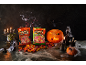 Bonbons fruités d'Halloween en sachets, citrouilles, bougies et toiles d'araignée sur fond sombre.