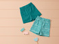 Deux paires de shorts bleus, l'un à rayures et l'autre uni, sur un fond en bois.
