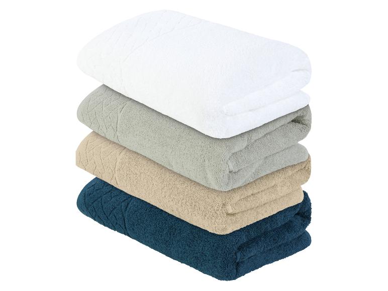 Pile de serviettes de bain en blanc, gris, beige et bleu foncé.