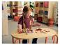Une jeune fille jouant avec un puzzle en bois du corps humain LUPILU® sur une table.