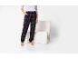 Pantalon de pyjama à carreaux foncés avec t-shirt gris et poignets, à côté d'un fauteuil blanc.